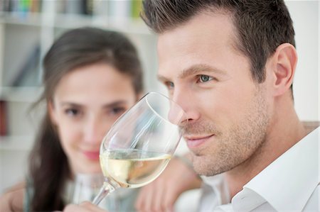 Man drinking white wine with his wife in the background Stock Photo - Premium Royalty-Free, Code: 6108-06167413