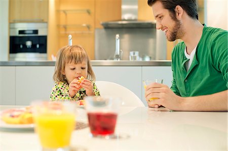 simsearch:6108-06167436,k - L'homme et la fille à la table du petit déjeuner Photographie de stock - Premium Libres de Droits, Code: 6108-06167419