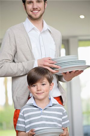 person in white polo shirt - Man and son arranging plates for lunch Stock Photo - Premium Royalty-Free, Code: 6108-06167541