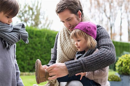 dressing - Man putting on shoe to his daughter Stock Photo - Premium Royalty-Free, Code: 6108-06167598