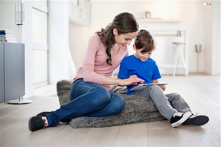 Femme regardant son fils à l'aide d'une tablette numérique Photographie de stock - Premium Libres de Droits, Code: 6108-06167537