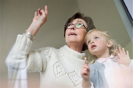 senior female cute - Woman with her granddaughter looking through a window Stock Photo - Premium Royalty-Free, Code: 6108-06167632