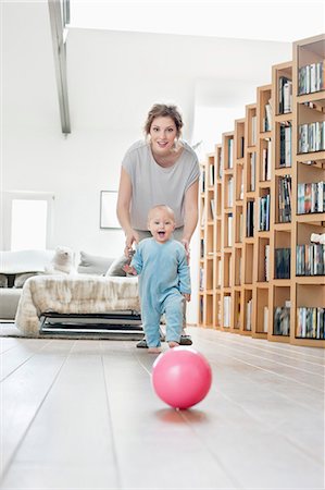 smiling baby pictures - Woman playing with her daughter walking towards a ball Stock Photo - Premium Royalty-Free, Code: 6108-06167723