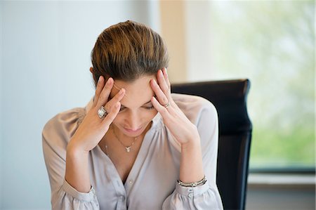 Close-up of a businesswoman suffering from a headache in an office Stock Photo - Premium Royalty-Free, Code: 6108-06167843