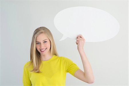people in yellow - Woman holding a speech bubble and smiling Stock Photo - Premium Royalty-Free, Code: 6108-06167857