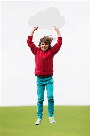 Boy holding a thought bubble and jumping Stock Photo - Premium Royalty-Free, Code: 6108-06167858