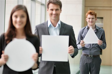 simsearch:6108-06167871,k - Business executives holding geometrical shaped placards in an office Stock Photo - Premium Royalty-Free, Code: 6108-06167867