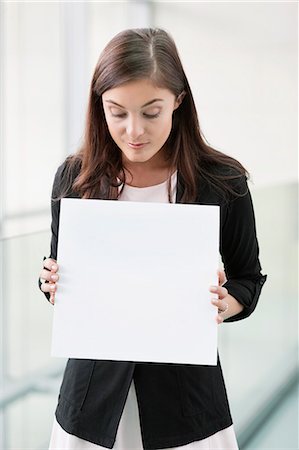 sign - Businesswoman holding a blank placard in an office Stock Photo - Premium Royalty-Free, Code: 6108-06167884