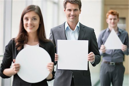 sign europe - Business executives holding geometrical shaped placards in an office Stock Photo - Premium Royalty-Free, Code: 6108-06167886