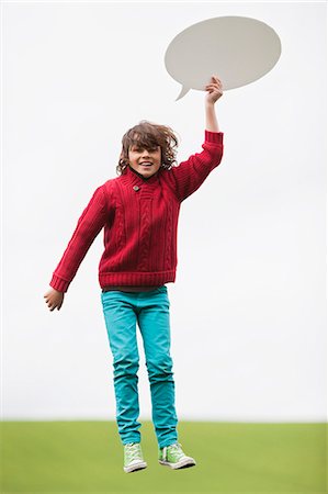 Boy holding a speech bubble in a field Stock Photo - Premium Royalty-Free, Code: 6108-06167889