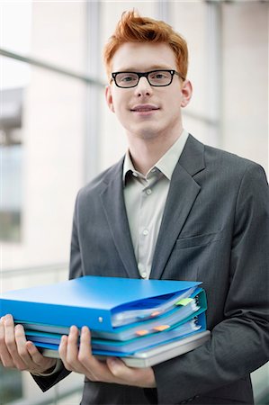 portrait suit - Portrait of a businessman holding files in an office Stock Photo - Premium Royalty-Free, Code: 6108-06167838