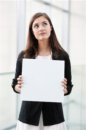 sign europe - Businesswoman holding a blank placard and thinking in an office Stock Photo - Premium Royalty-Free, Code: 6108-06167900