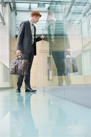 Businessman peeking through glass in a corridor Stock Photo - Premium Royalty-Free, Code: 6108-06168057