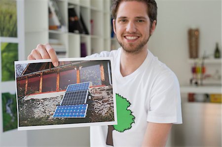 environmental issues and alternative energy - Man showing an ecological poster of solar panel Stock Photo - Premium Royalty-Free, Code: 6108-06168107