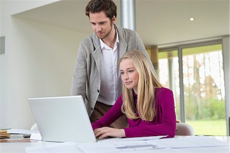 Man looking at a woman working on a laptop Stock Photo - Premium Royalty-Free, Code: 6108-06168136