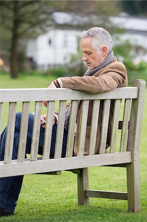 sitting on park bench - Man text messaging on a mobile phone in a park Stock Photo - Premium Royalty-Free, Code: 6108-06168356