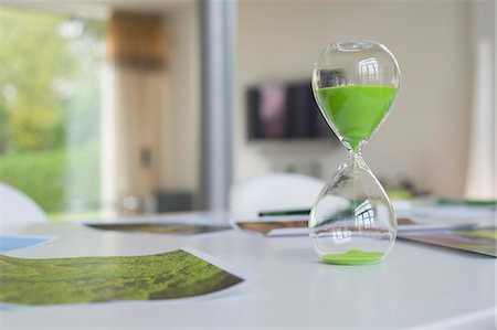 Green hourglass and ecological poster on a table Stock Photo - Premium Royalty-Free, Code: 6108-06168373