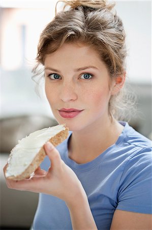 Portrait of a woman eating toast with cream spread on it Stock Photo - Premium Royalty-Free, Code: 6108-06168412