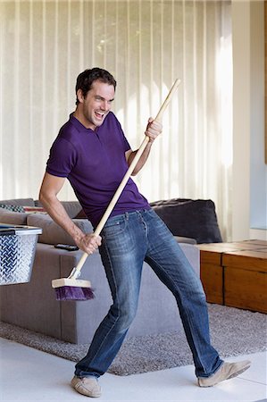 playing guitar on sofa - Man holding a mop as a guitar Stock Photo - Premium Royalty-Free, Code: 6108-06904567