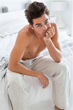 Serious man sitting on the bed Stock Photo - Premium Royalty-Free, Code: 6108-06904566