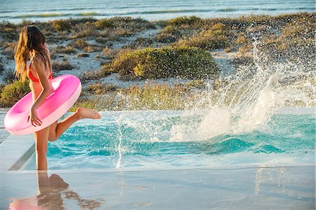 splashed with water - Woman enjoying in a swimming pool on the beach Stock Photo - Premium Royalty-Free, Code: 6108-06904641