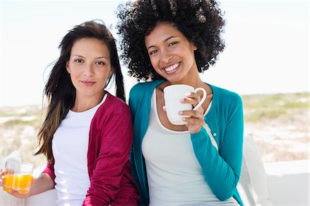 friends drinking juice - Portrait of a two female friends smiling Stock Photo - Premium Royalty-Free, Code: 6108-06904600