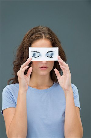 Woman hiding behind paper with false eyes Stock Photo - Premium Royalty-Free, Code: 6108-06904798