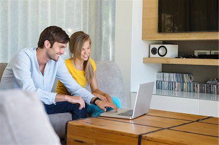 Man and his daughter sitting on a couch looking at a laptop Foto de stock - Sin royalties Premium, Código: 6108-06904897