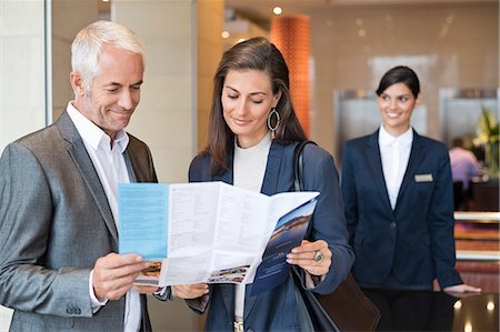 Business couple reading a brochure in front of a hotel reception counter Fotografie stock - Premium Royalty-Free, Codice: 6108-06904981