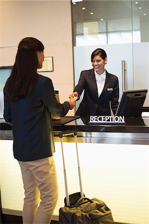 person desk rearview - Businesswoman paying with a credit card at the hotel reception counter Stock Photo - Premium Royalty-Free, Code: 6108-06904986