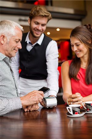 female holding a mobile phone - Waiter showing credit card reader to a couple on a table in a restaurant Stock Photo - Premium Royalty-Free, Code: 6108-06904988