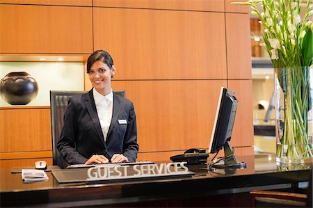 Portrait of a receptionist smiling at the hotel reception counter Stock Photo - Premium Royalty-Free, Code: 6108-06904990