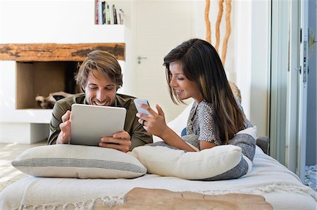 phone woman bed - Couple lying on the bed and using electronic gadgets Stock Photo - Premium Royalty-Free, Code: 6108-06904900