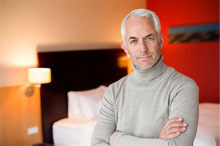 Portrait of a man with arms crossed in a hotel room Stock Photo - Premium Royalty-Free, Code: 6108-06904929