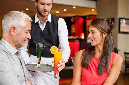 Waiter serving drinks to a couple in a restaurant Photographie de stock - Premium Libres de Droits, Code: 6108-06905040