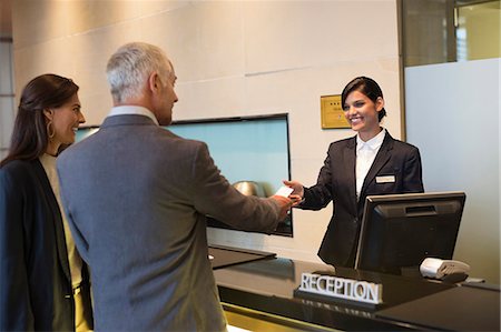 standing customer service - Business couple getting key card at the hotel reception counter Stock Photo - Premium Royalty-Free, Code: 6108-06905055