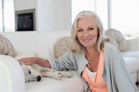 Portrait of a smiling woman stroking her dog lying on couch Photographie de stock - Premium Libres de Droits, Code: 6108-06905090