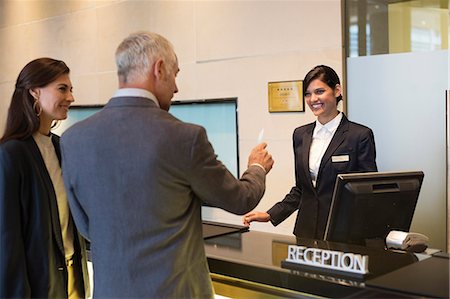 standing customer service - Business couple getting key card at the hotel reception counter Stock Photo - Premium Royalty-Free, Code: 6108-06905000