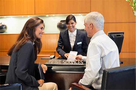 Business couple talking at a hotel reception counter Stock Photo - Premium Royalty-Free, Code: 6108-06905007