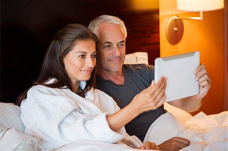 Couple watching movie on a digital tablet in a hotel room Stock Photo - Premium Royalty-Free, Code: 6108-06905020