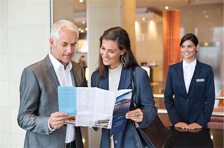 Business couple reading a brochure in front of a hotel reception counter Stock Photo - Premium Royalty-Free, Code: 6108-06905021