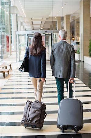 people in hotel - Business couple pulling suitcases in a hotel lobby Stock Photo - Premium Royalty-Free, Code: 6108-06905026