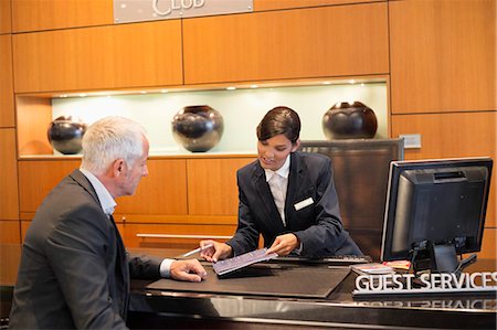 Receptionist showing a brochure to a businessman at a hotel reception counter Photographie de stock - Premium Libres de Droits, Code: 6108-06905036