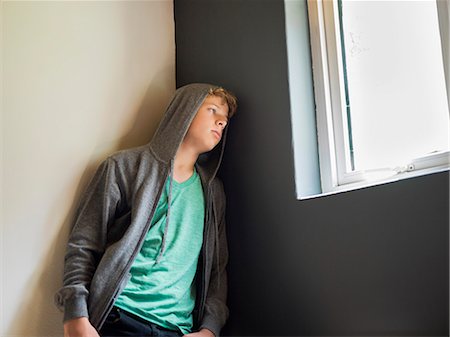 Teenage boy leaning against a wall and thinking Stock Photo - Premium Royalty-Free, Code: 6108-06905189