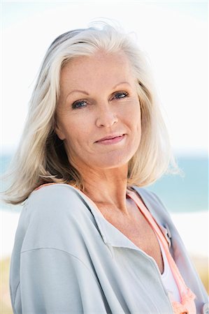 silver hair smile alone - Portrait of a woman smiling on the beach Stock Photo - Premium Royalty-Free, Code: 6108-06905120