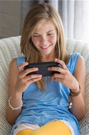Girl playing a video game and smiling Photographie de stock - Premium Libres de Droits, Code: 6108-06905219