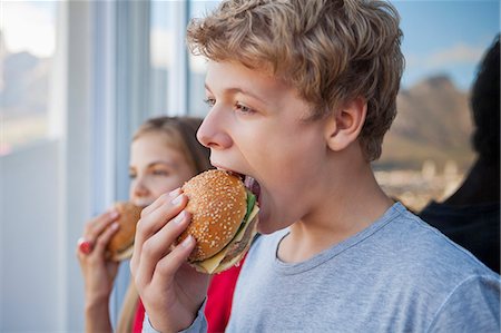 food and fast food - Close-up of two friends eating hamburger Stock Photo - Premium Royalty-Free, Code: 6108-06905231