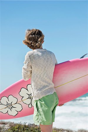 Boy holding a surfboard on the beach Stock Photo - Premium Royalty-Free, Code: 6108-06905236