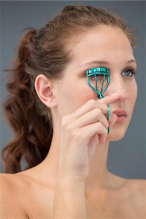 simsearch:6108-06906361,k - Close-up of a woman curling her eyelashes with eyelash curler Foto de stock - Sin royalties Premium, Código: 6108-06905367
