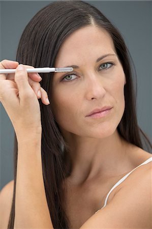 Portrait of a woman applying eyeliner Stock Photo - Premium Royalty-Free, Code: 6108-06905370